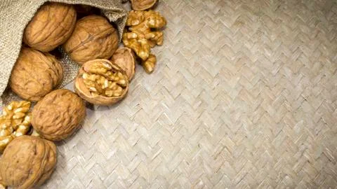 Arrangement of walnuts shells and walnut kernels in burlap sack on light wicker Foto stock