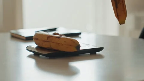 Arranging bananas near notebook under soft light. Influencerstyle scene of Stock Footage 342424091