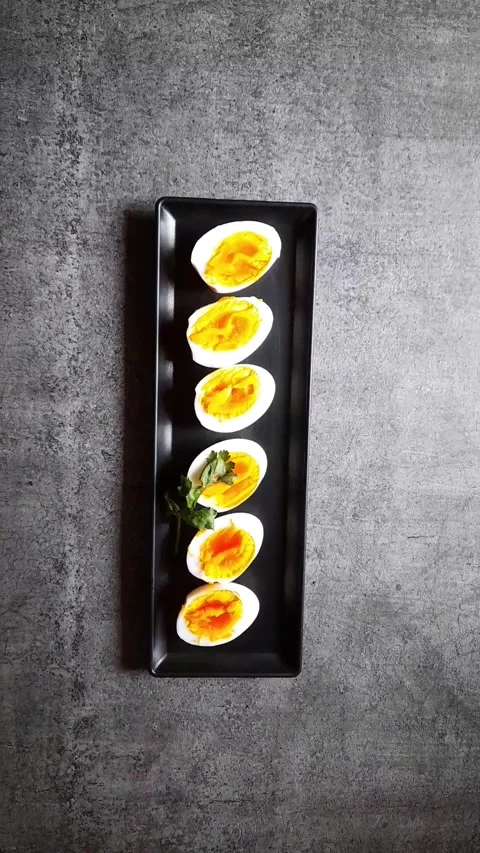 Arranging egg slices on a black tray along with bread slices. Stock Footage 154129058