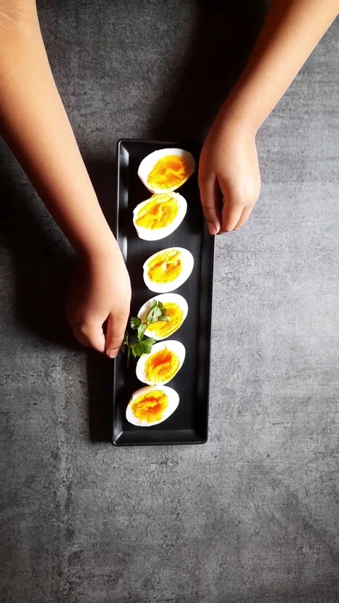 Arranging egg slices on a black tray Stock Footage 154129093