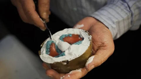 Arranging the flasking material and removing excess plaster of parris in Video stock 107753195