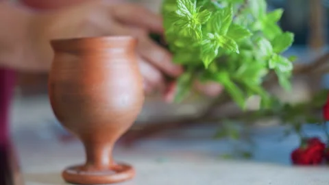 Arranging fresh mint into decorative ceramic container. Closeup of mint leaves Stock Footage 346404749