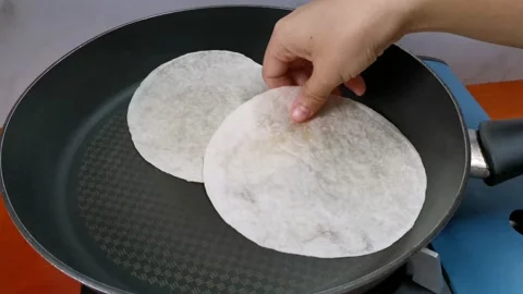 Arranging Plain Tortilla Wraps on a Non Stick Pan Stock Footage 162876503
