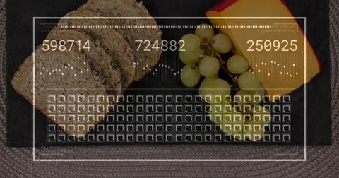 Arranging seeded bread, halved green grapes, cheese wedge red rind on slate at Stock Photos
