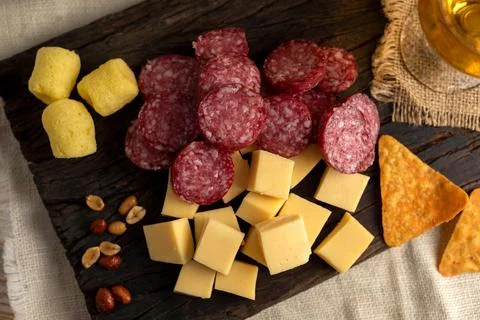 Array of assorted cheese, sausage, nachos and nuts on a wooden platter Foto stock
