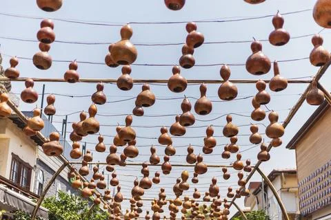 An array of beautiful, handmade gourds hangs from strings above a lively mark Stock Photos
