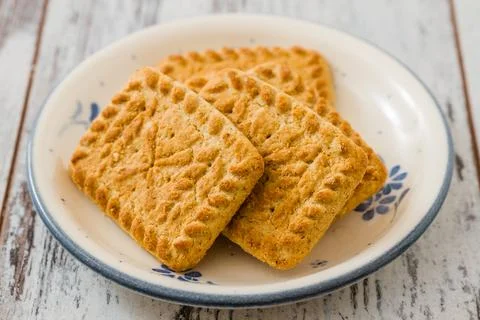 Array of biscuits neatly arranged on a plate, on white wooden table. Foto stock