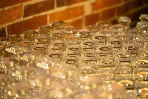 Array of clear drinking glasses sits atop a table, arranged in an organized mann Stock Photos