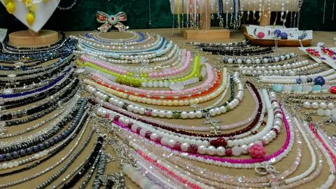 Array of colorful beaded necklaces arranged on display table with mixed pearls Stock Photos
