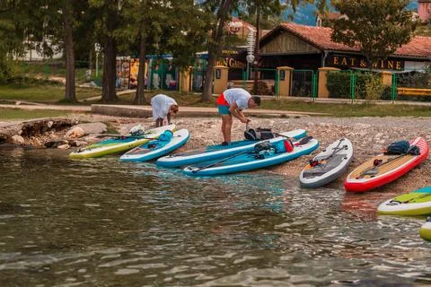 Array of colorful paddleboards on a pebbled lakeshore ready for adventure Foto stock