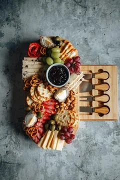 Array of delicious snacks including cheese, olives, grapes, and crackers Stock Photos