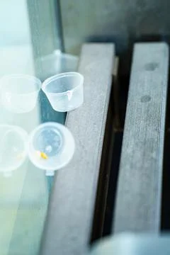 Array of empty plastic condiment and snack containers rests on a bench, sym.. Foto stock