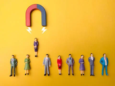 Array of figurines arranged in a pattern with a magnet and an arrow pointing in Stock Photos