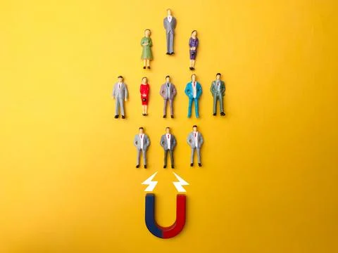 Array of figurines arranged in a pattern with a magnet and an arrow pointing in Stock Photos