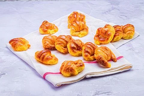 Array of freshly-baked croissants arranged alongside a folded white napkin Stock Photos