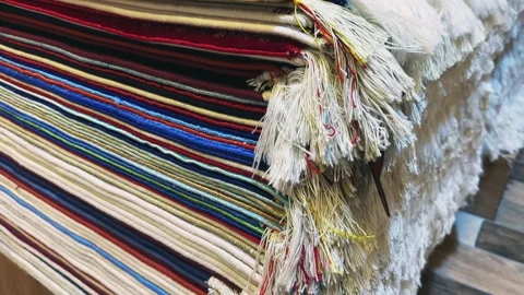 Array of intricately colored rugs stacked neatly within a traditional marketp Stock Footage 328186113