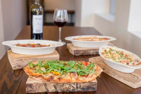 An array of Italian dishes lay on a table with a bottle of red wine Fotos de archivo