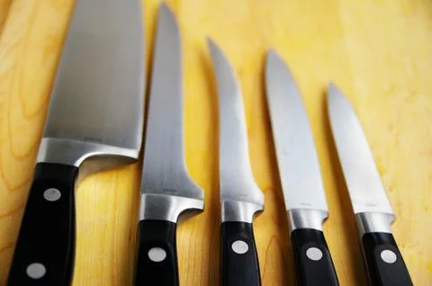 Array of kitchen knives on a wooden cutting board Stock Photos
