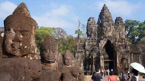 Array of large stone statues in a park with people walking by Fotos de archivo