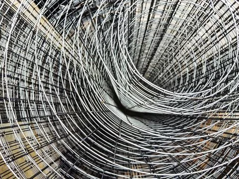 An array of metal wires creates a complex, swirling pattern against a neutral Stock Photos