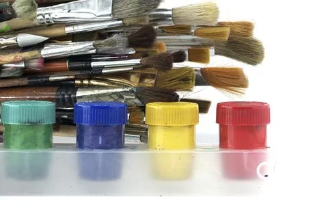 Array of paintbrushes of different sizes and colors alongside cans of acrylic Foto stock
