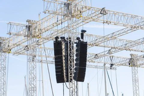 Array of professional line array speakers suspended from a metal truss at ... Stock Photos