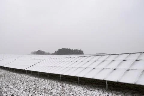 Array of solar modules in solar park on field completely covered with snow in Fotos de archivo