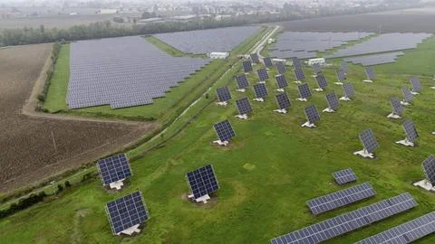 An array of solar panels on a green field under an overcast sky 写真素材