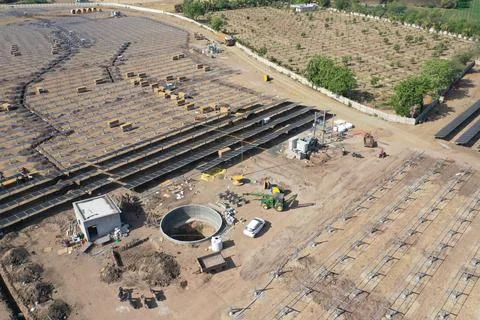 Array of solar panels installed in a rural field, with electrical equipment visi Foto stock