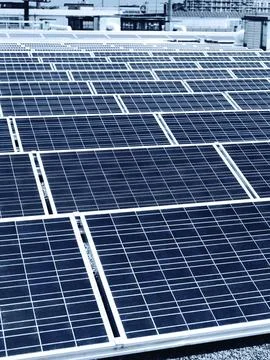 Array of solar panels in rows on a roof of a building in a city Foto stock
