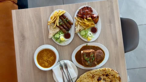 An array of spicy indian dishes on plates and on a table Vídeo Stock 345260881