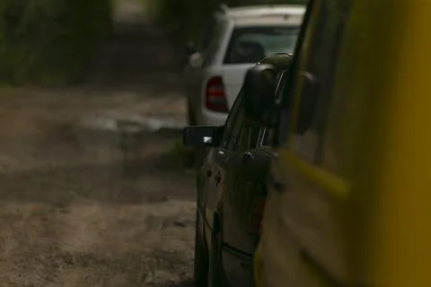 An array of vehicles halted along muddy country lane shaded by leafy branches 写真素材