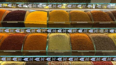 Array of vibrant oriental spices fills containers on shelf. Stock Photos