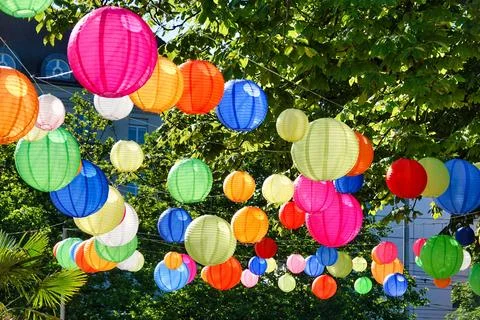 Array of vibrant paper lanterns are suspended from a lush tree in the city of Au Stock-Fotos