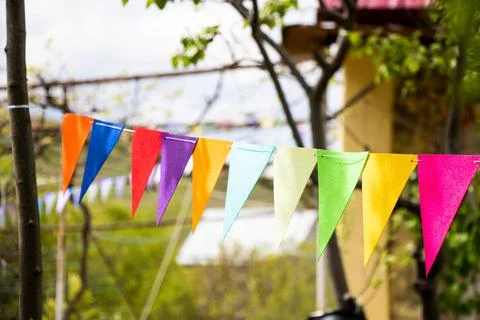 Array of vibrant pennants adorning the trees outside a residence. Stock Photos