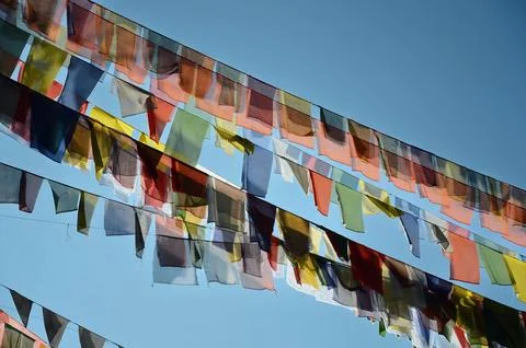 Array of vibrantly colored prayer flags fluttering in the wind against a clear, Foto stock