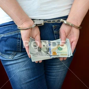 An arrested girl with handcuffed hands with a huge amount of dollar bills. Ba Stock Photos