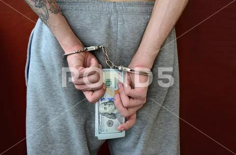 An arrested guy in gray pants with handcuffed hands holds a huge amount of do Stock Photos