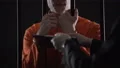 Arrested man behind prison bars signing document and guard taking handcuffs off 4k or 4k+ Resolution