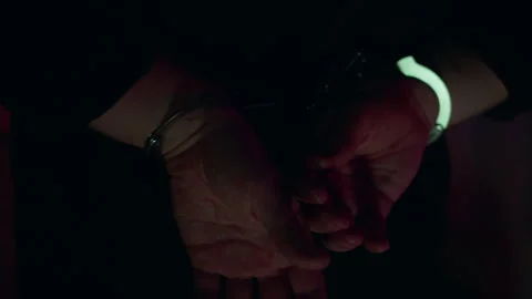 Arrested man in handcuffs. Handcuffed hands are illuminated by police flashers Stock Footage 307938317