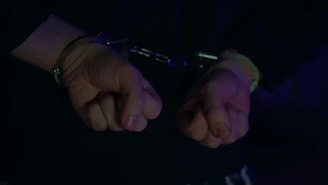 Arrested mans hands cuffed behind his back. A darkened room. Flashing blue and Stock Footage 314509772