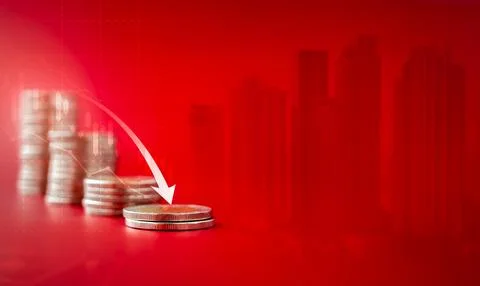 Arrow pointing down over the coin stack as a graph step on red city buildin.. Stock Photos