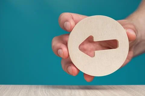 Arrow pointing left on a blue background. Banner with an arrow in a wooden Stock Photos