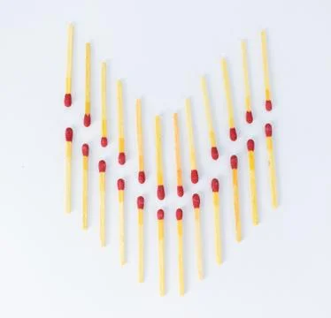 Arrow shape made of two rows of red match sticks on a white background Stock Photos