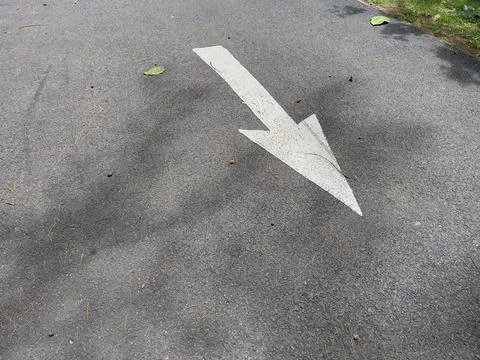 Arrow sign on the road with shadow of tree on the ground Stock Photos