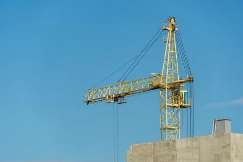 An arrow of working construction cranes against a background of blue sky and  Stock Photos