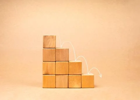 Arrows jumping down on wood cube graph step blocks, decrease business graph.. 库存照片
