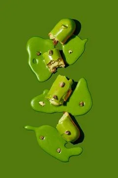 Art with an eclair. Broken eclair in puddles of icing on green background. .. Stock Photos