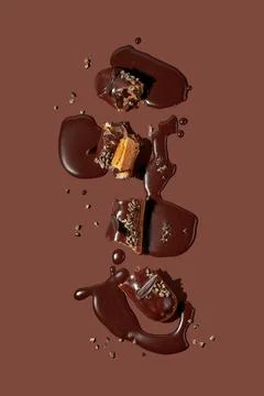 Art with an eclair. Broken eclair in puddles of icing on brown background. .. Stock Photos
