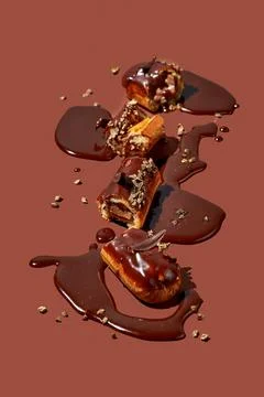 Art with an eclair. Broken eclair in puddles of icing on brown background. .. Foto stock